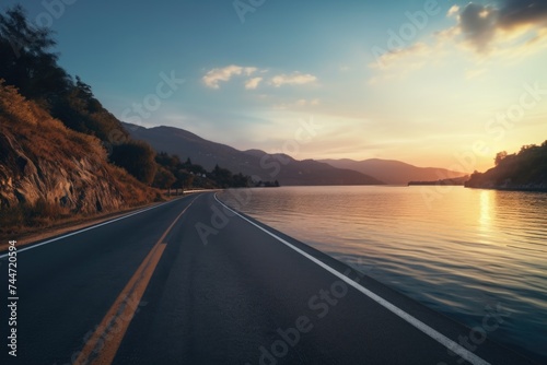 A scenic road running alongside a peaceful body of water. Perfect for travel and nature themed designs
