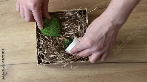 Close-up of the hands of a man who is packing a gift. The gift is decorated with paper filler. The paper filler preserves the fragile goods. Eco-friendly paper filler for gift wrapping.