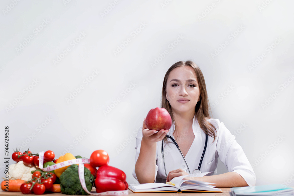 Smiling nutritionist in her office, she is showing healthy vegetables and fruits, healthcare and diet concept. Smiling nutritionist in her office, she is showing healthy vegetables and fruits, healthcare and diet concept.