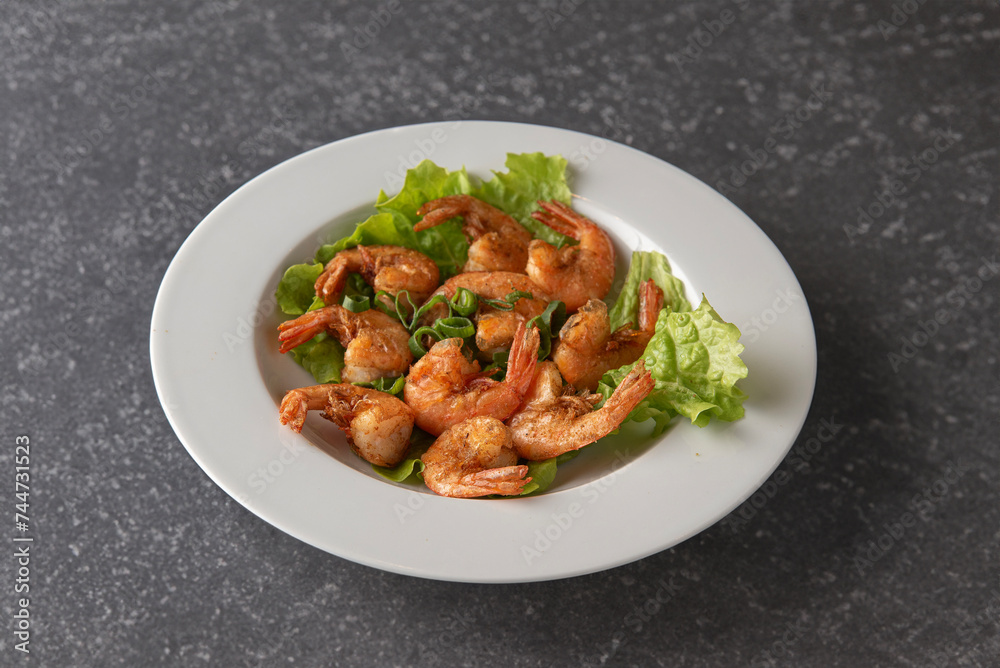 plate of shrimp cooked with salt and pepper with salad centered on gray background
plate of shrimp cooked with salt and pepper with salad centered on gray background