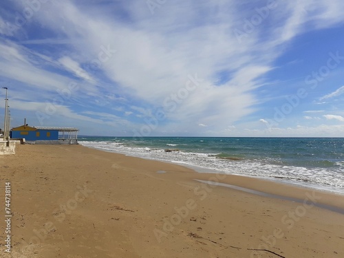 Il mare d'inverno, il cielo blu con qualche nuvoletta bianca, la spiaggia deserta, una biccola baracca sulla spiaggia. photo