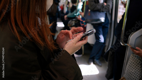 A Japanese commuter, deeply engaged with her smartphone. A woman using phone © REC Stock Footage