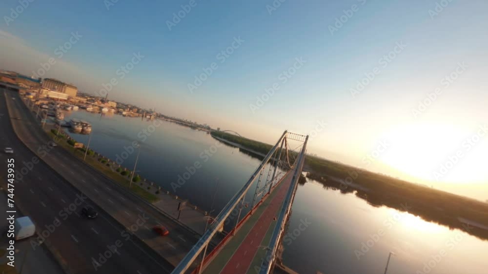 FPV, Pedestrian bridge at Kyiv city . bridge over Dnipro river, golden hour, Drone aerial view Kyiv pedestrian bridge, Truchaniv island and Dnieper river on a beautiful sunny day. Capital of Ukraine