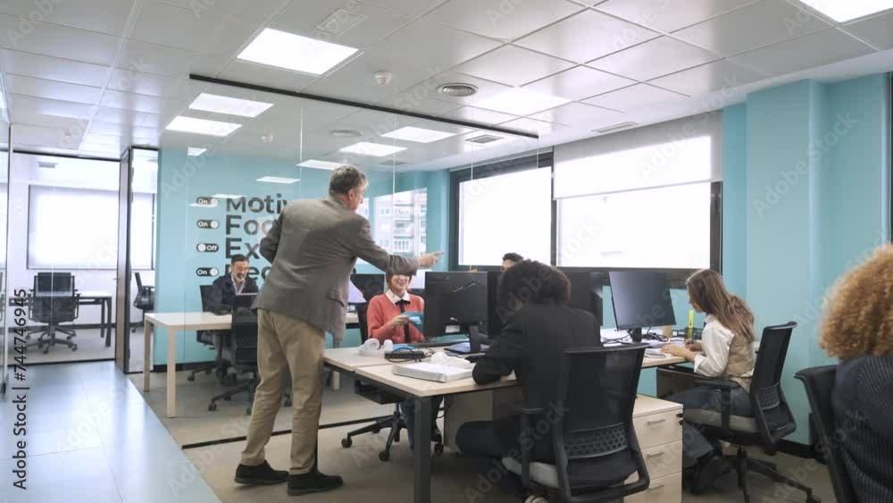 Manager giving files to employees in coworking workspace Manager giving files to employees in coworking workspace