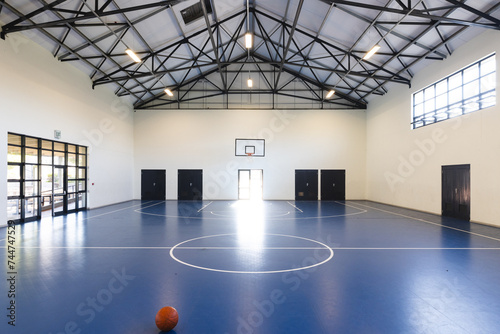 An empty basketball court awaits players at a school gym photo