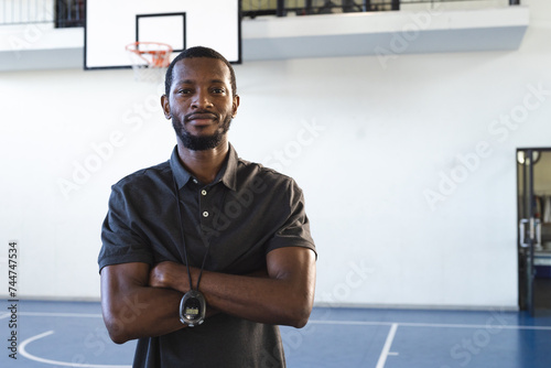 Confident African American coach stands in a school gym, with copy space photo