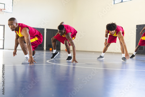 Diverse basketball players practice in an indoor court photo