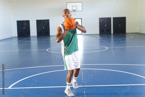 African American man practices basketball in an indoor court photo