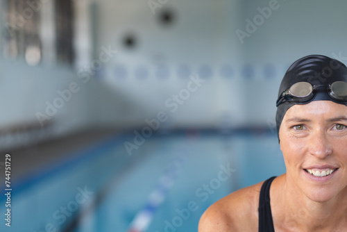 Caucasian female athlete swimmer smiles at the poolside, with copy space photo