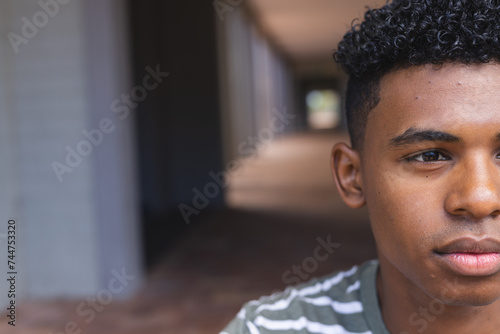 Teenage biracial boy looks thoughtful at high school, with copy space photo