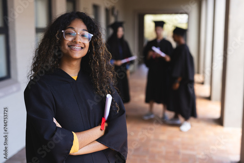 Proud graduate in cap and gown holding a diploma at high school