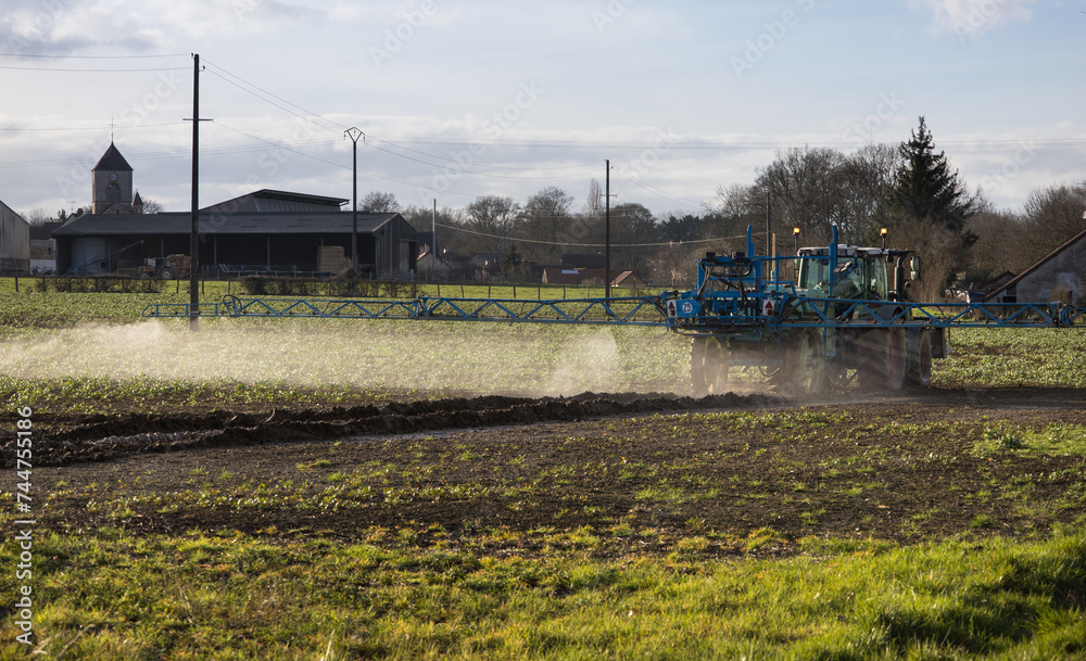 Pulvérisation de pesticides par tracteur sur un champ avec pulvérisateur au printemps, un danger pour les agriculteurs et la planète Pulvérisation de pesticides par tracteur sur un champ avec pulvérisateur au printemps, un danger pour les agriculteurs et la planète