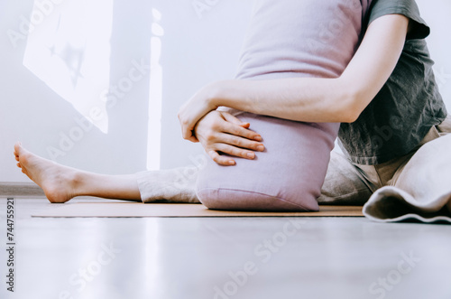 Woman in casual clothing practicing yin yoga butterfly pose leaning on bolster