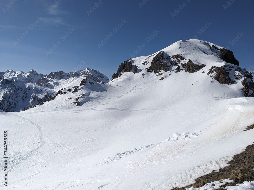 Snow topped alpine mountain rock blue sky snow tracks