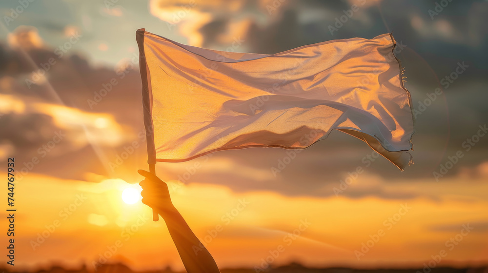 Person holding up a white flag at sunset, concept of peace - obrazy, fototapety, plakaty 