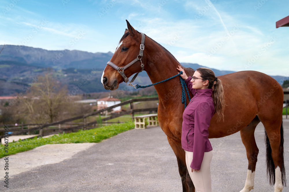 Obraz premium A serene outdoor setting frames a young equestrian as she lovingly bonds with a majestic bay horse.