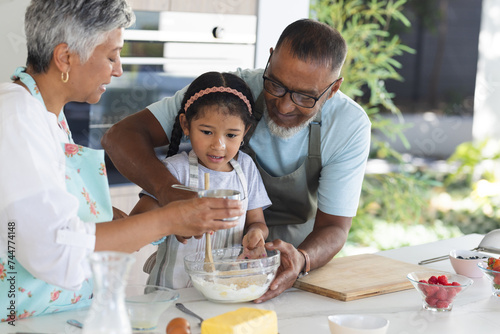 Biracial grandparents and granddaughter enjoy baking together at home photo