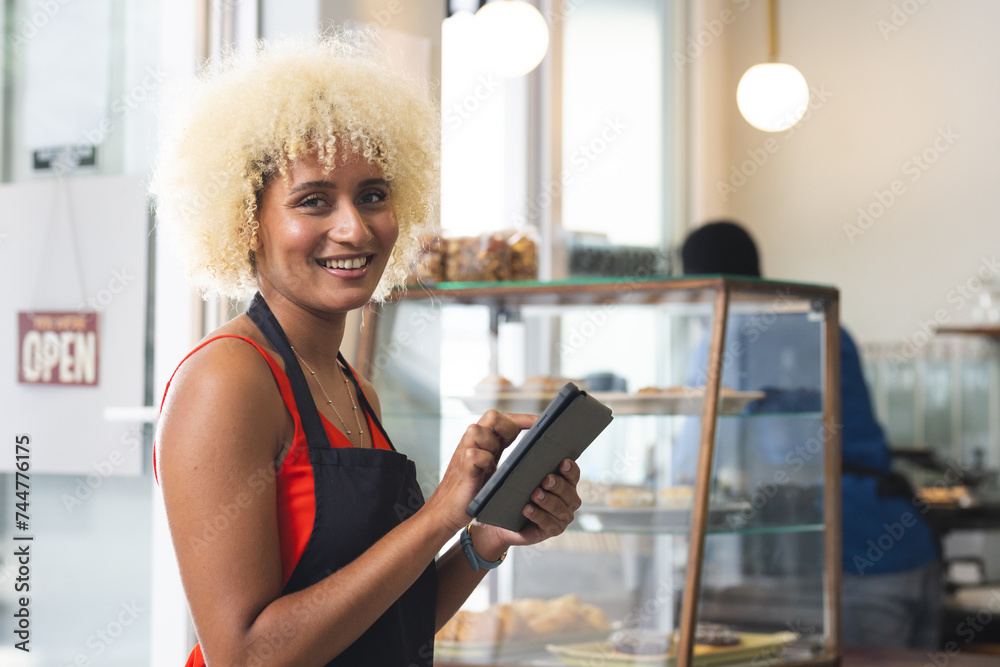 A smiling biracial woman operates a point of sale system in a cafe, with copy space A smiling biracial woman operates a point of sale system in a cafe, with copy space