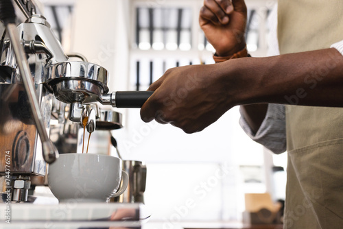 An African American barista prepares espresso at a coffee machine photo