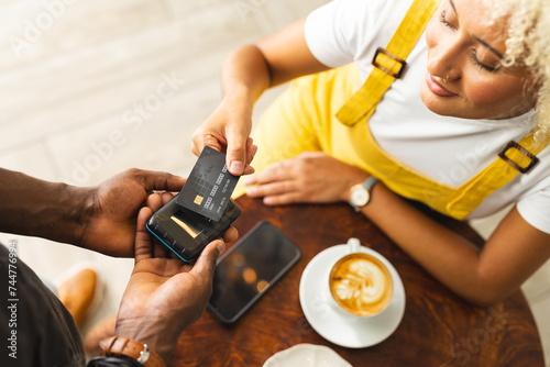 Young African American man and biracial woman using a card for mobile payment at a cafe photo