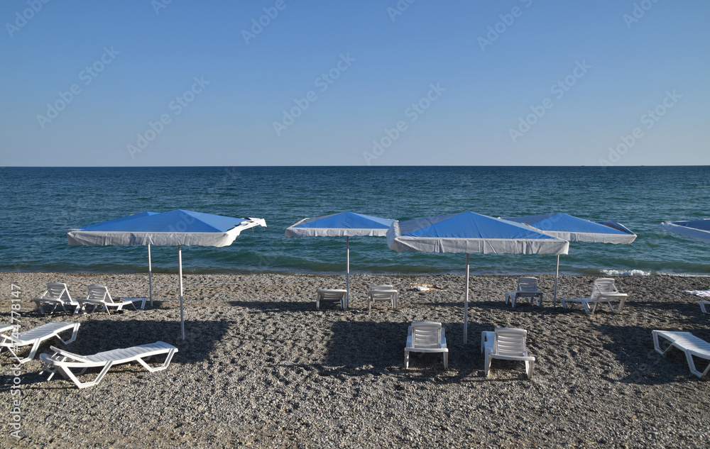 Sea beach with blue beach umbrellas and white sun loungers Sea beach with blue beach umbrellas and white sun loungers