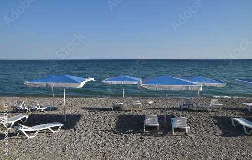 Sea beach with blue beach umbrellas and white sun loungers © abentson