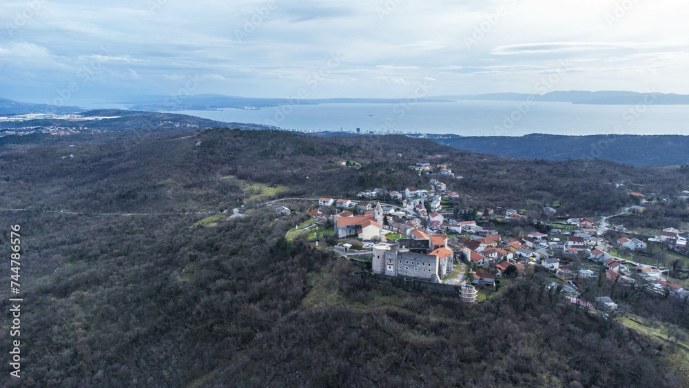 Fototapeta premium Aerial view of the charming village of Grobnik near Rijeka, Croatia, showcasing an old fortress atop a hill and a quaint church