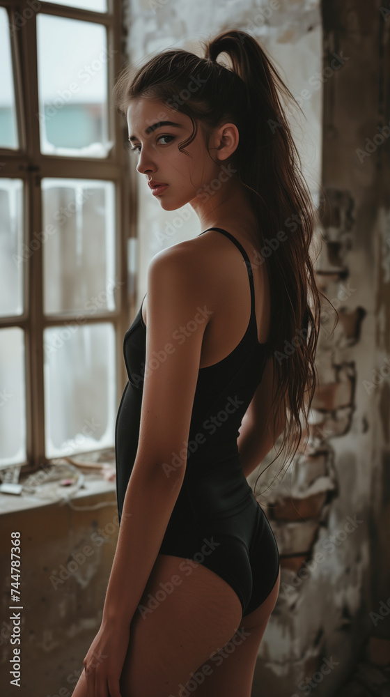 woman in black swimsuit standing by the window