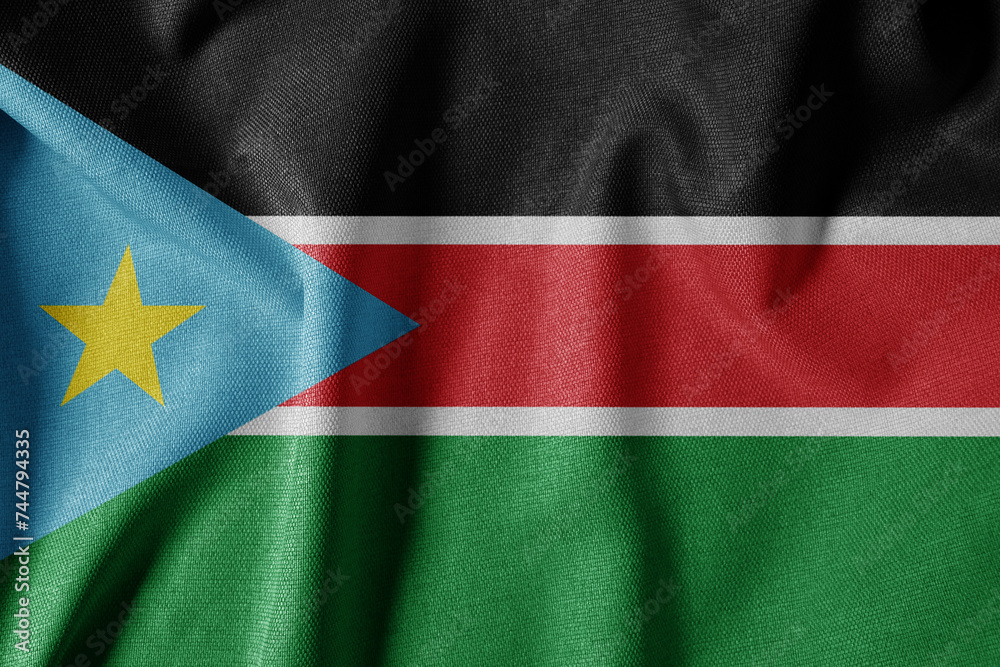 Fototapeta premium National Flag on Textured Fabric Background. Silk textured flag, realistic wave and flag look. SS Flag of South Sudan