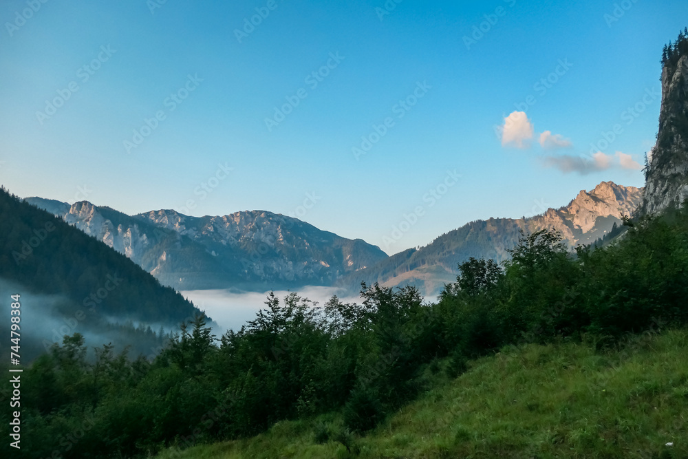 Sunrise view over majestic mountain peak in Hochschwab massif, Styria, Austria. Hiking trail in forest. Austrian Alps in summer. Wanderlust concept. First morning sunlight on top of rock formation