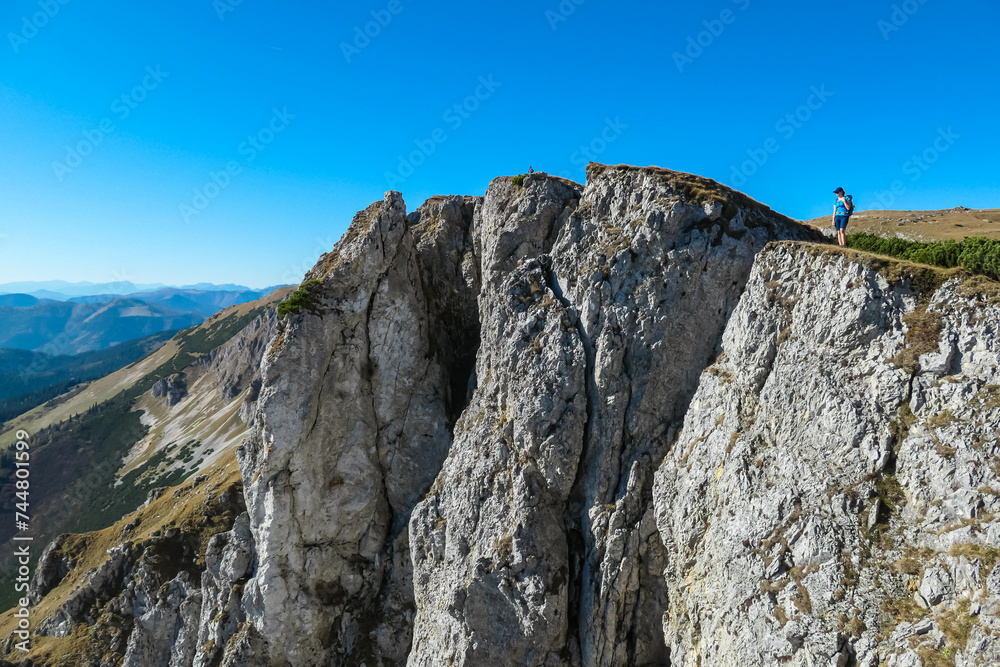 Hiker Woman on edge of steep cliff on top of mountain peak Hohe Veitsch, Mürzsteg Alps, Styria, Austria. Idyllic hiking trail alpine terrain. Wanderlust remote Austrian Alps in autumn. Rock formation Hiker Woman on edge of steep cliff on top of mountain peak Hohe Veitsch, Mürzsteg Alps, Styria, Austria. Idyllic hiking trail alpine terrain. Wanderlust remote Austrian Alps in autumn. Rock formation