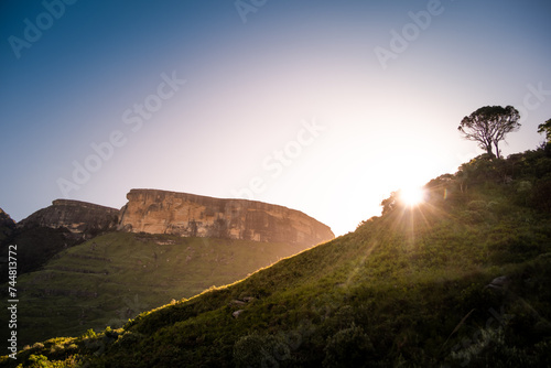 Sun setting behind a hill in Royal Natal park in Drakensberg, South Africa © Yann