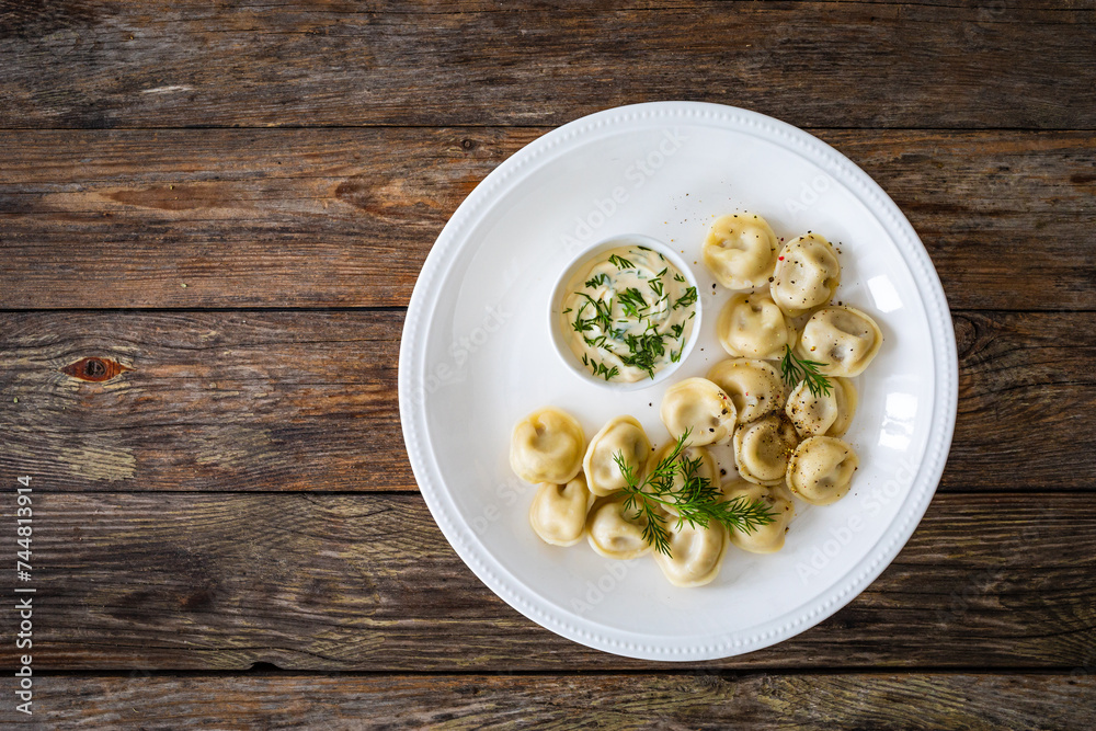 Pelmeni - dumplings filled minced meat on wooden table
Pelmeni - dumplings filled minced meat on wooden table