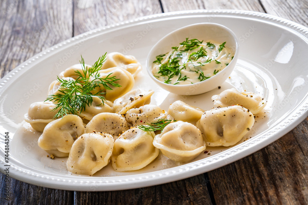 Pelmeni - dumplings filled minced meat on wooden table
Pelmeni - dumplings filled minced meat on wooden table