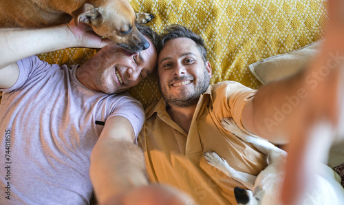 Photography selfie of a homosexual couple with their dogs lying on the floor looking at the
