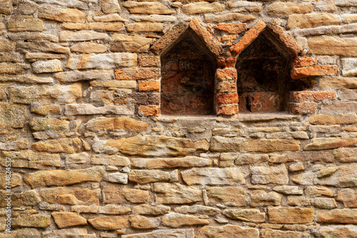 Old stone wall with two windows. Background texture. Close-up.