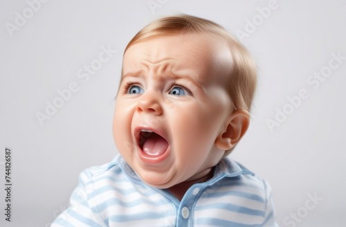 providing baby care. little Caucasian boy toddler crying out loud on white background, closeup