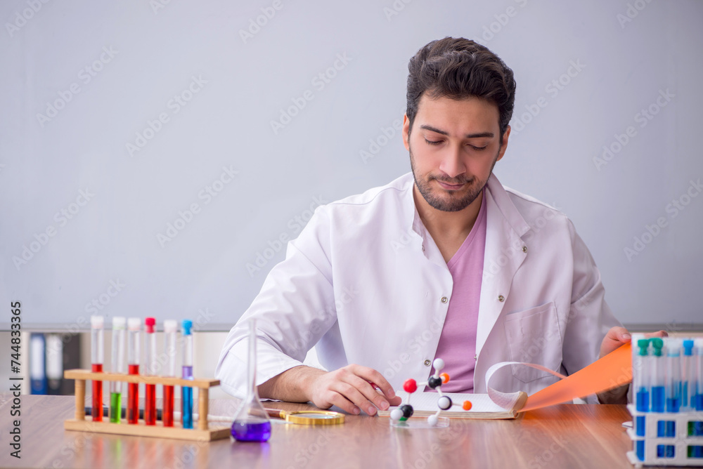 Young male chemistry teacher sitting in the classroom Young male chemistry teacher sitting in the classroom