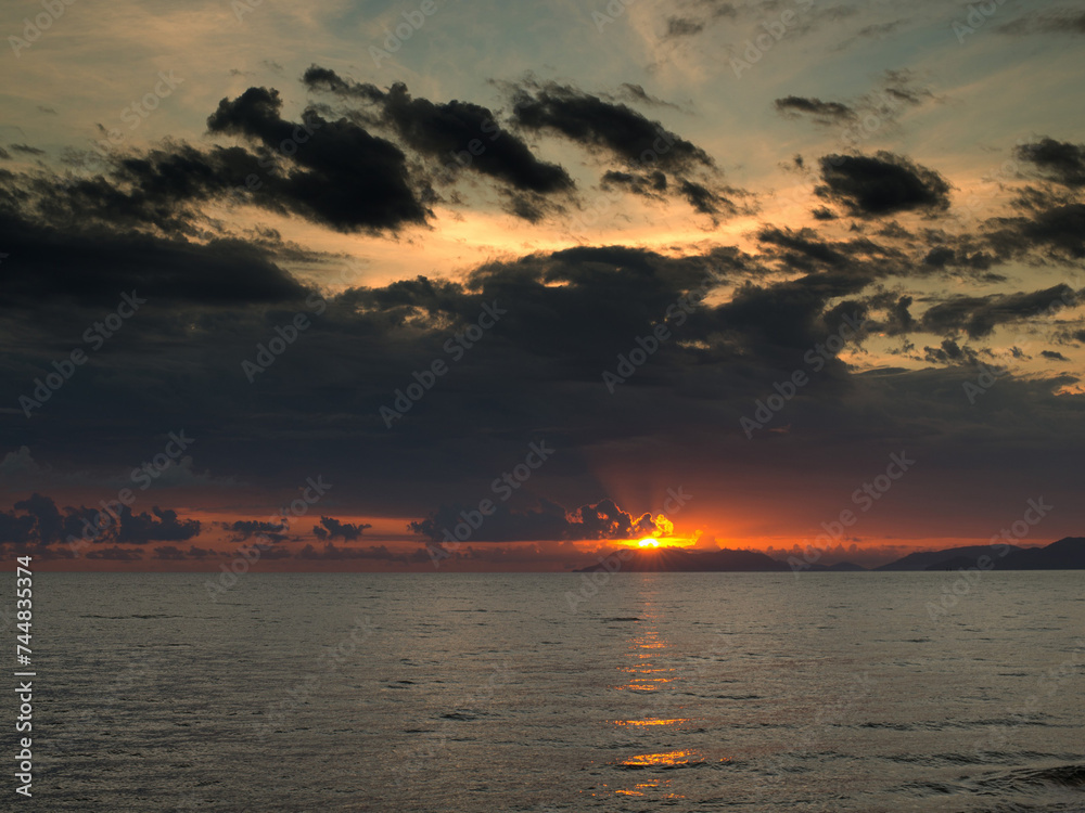 Fototapeta premium Golden morning light bathes Trinity Bay in Far North Queensland, illuminating the tranquil waters with a captivating glow.