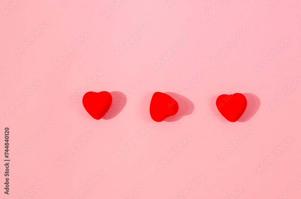 Valentine's Day concept. three red hearts on pink background.