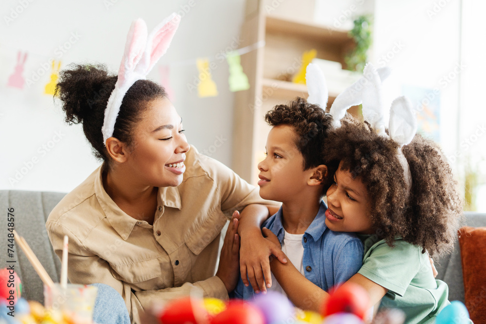 Happy Christian family : mother and cute kids wearing bunny ears embracing looking each other celebration Easter at home Happy Christian family : mother and cute kids wearing bunny ears embracing looking each other celebration Easter at home