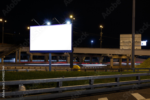 Illuminated empty billboard near a highway at night. Mock-up.