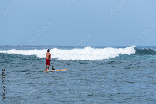 Stand up paddler waiting for waves to surf in the ocean