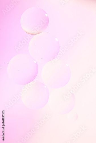 Macro drops of oil on the surface of the water. Delicate cosmetic bubbles background for advertising cosmetic products in soft pink tones.