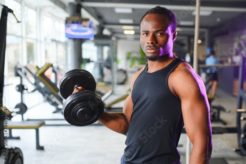 healthy african man working out with dumbbells in gym