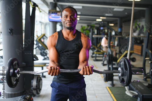 Portrait Of Athletic Man With Barbell In Hands Exercising At Gym