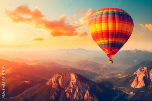 A colorful hot air balloon floats serenely in the sky at sunrise over a mountainous landscape.