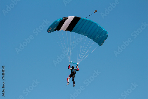 A skydiver with a blue parachute in the air