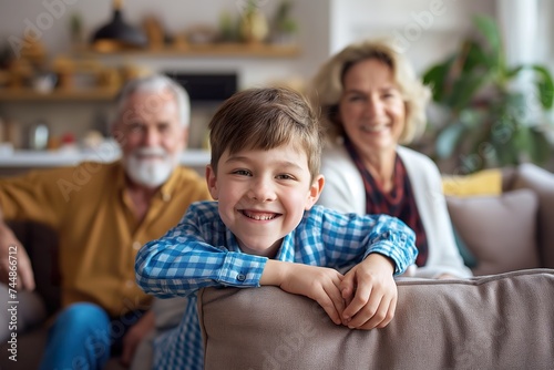 Cheerful little boy sitting with parents and grandmother on a couch at home.