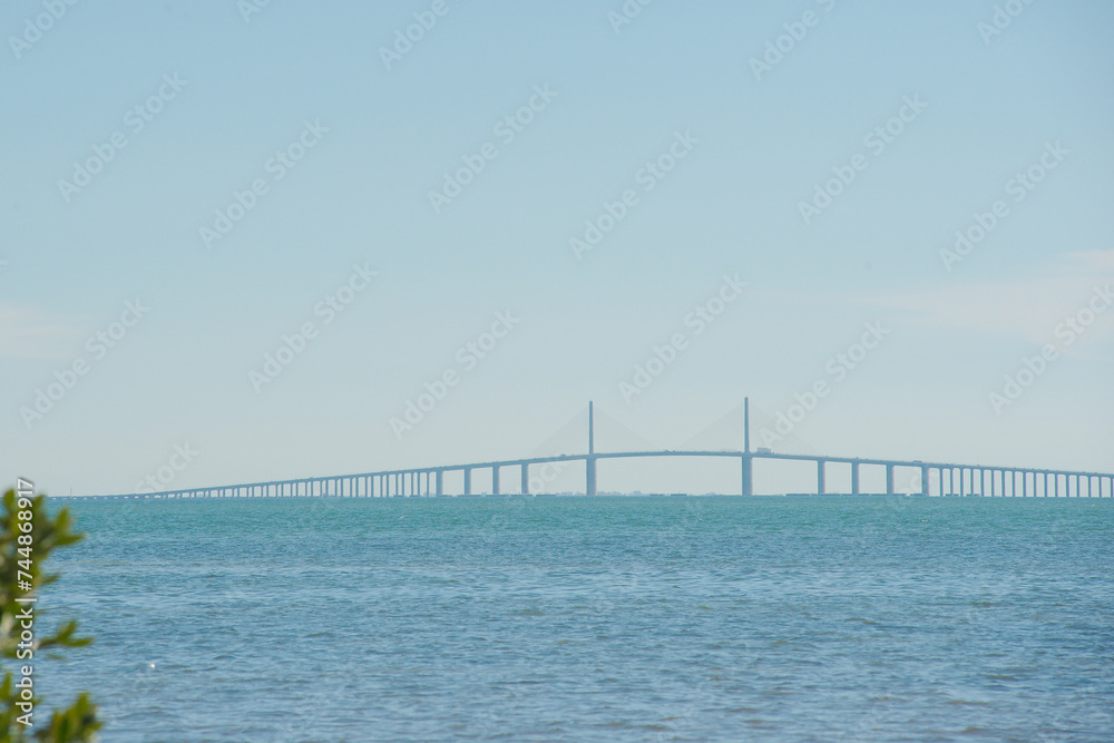 Wide View from beach at Maximo Park in St Petersburg Florida towards  the Sunshine Skyway bridge in Tampa Bay. Small waves on blue water late afternoon sun.  
